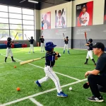 Hitclub youth baseball training with coaches and athletes practicing in vibrant indoor facility.